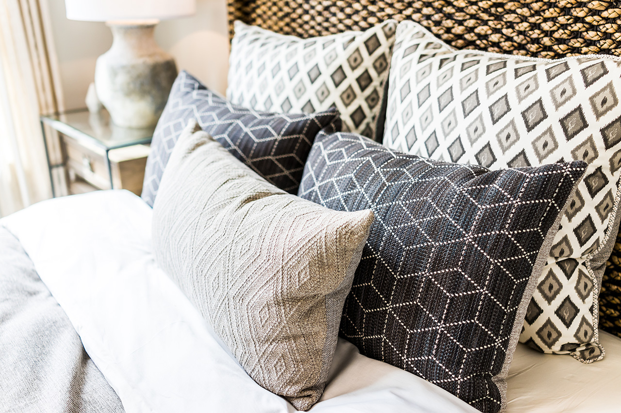 closeup-of-new-bed-comforter-with-decorative-pillows-headboard-in-bedroom-in-staging-model-home-house-or-apartment